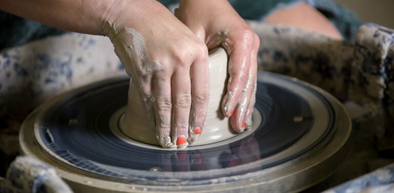 Hands sculpting pottery in class