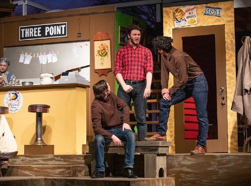 Three male students act in a theatre production.