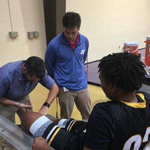 Athletic Training student puts bandage on basketball player's ankle