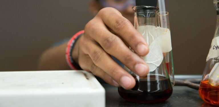 HSU biology student reaching for beaker