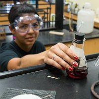 Chemistry student reaching for a beaker