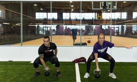 Two trainers lift kettlebells.