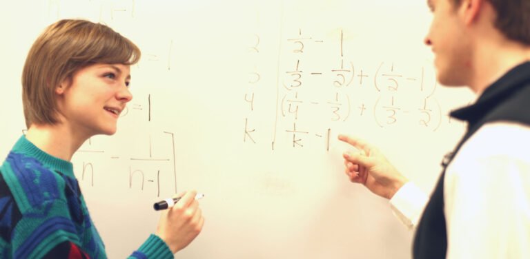 Professor and HSU solving math problems on white board