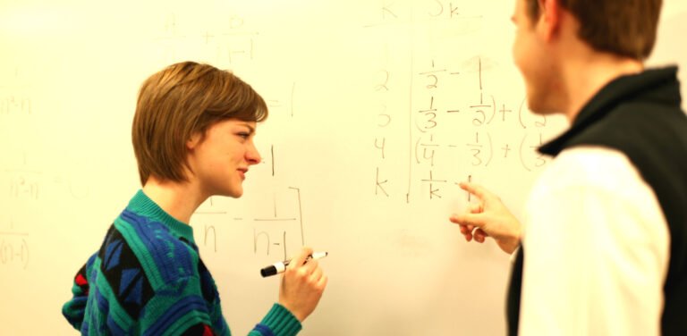 Professor and HSU solving math problems on white board