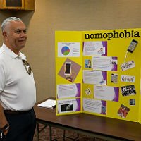 HSU faculty looking at student research project poster entitled nomophobia