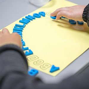 Child matching foam letters to their shapes on paper