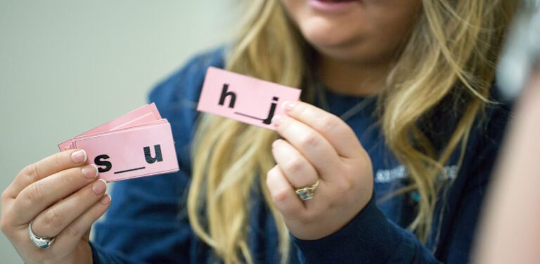 special education teacher holding up labeled cards with missing letters