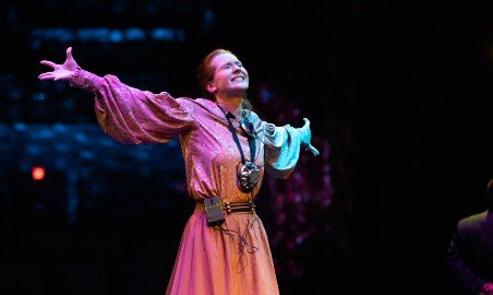 Female student sings in a theatre production.