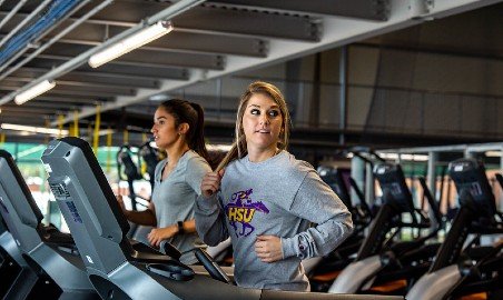 Two women running on treadmills.