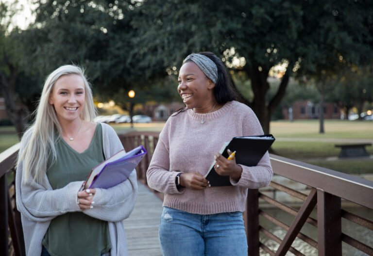 Photo of two smiling HSU students crossing a foot bridge on campus.