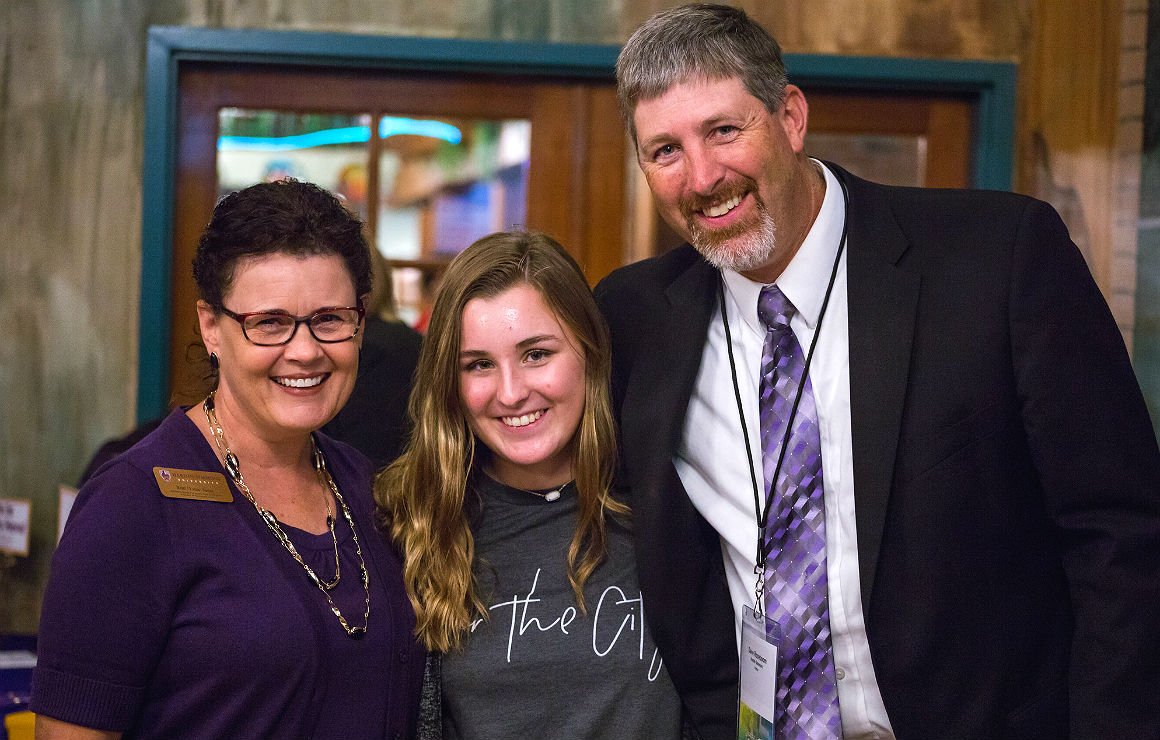 Two staff members and a student pose for a group photo.