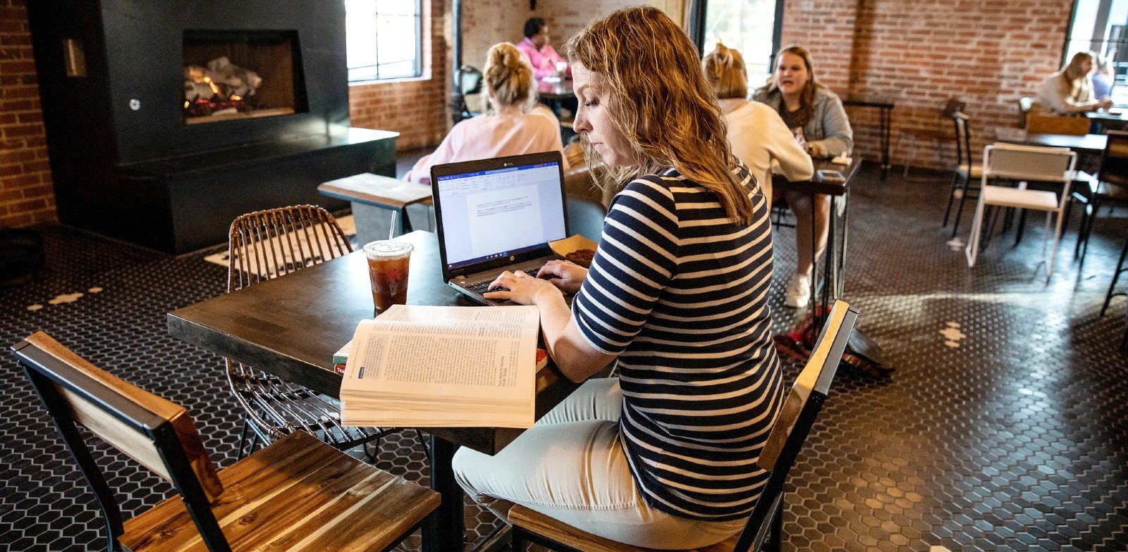 A graduate student works on a laptop in a coffee shop.