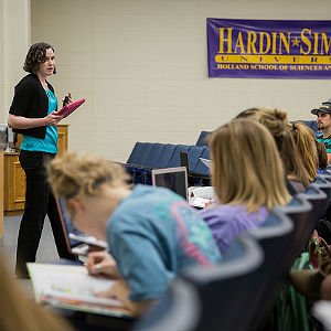 Student teacher speaks to young children taking notes