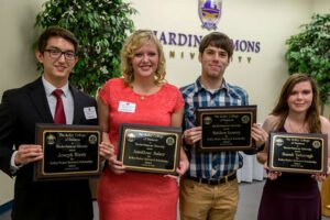 Students display their honors program plaques.