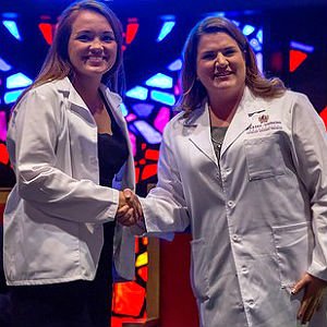 HSU Physician Assistant student and professor dressed in white lab coats shaking hands
