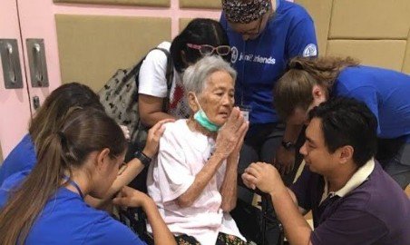 PT students praying with a lady during a mission trip.