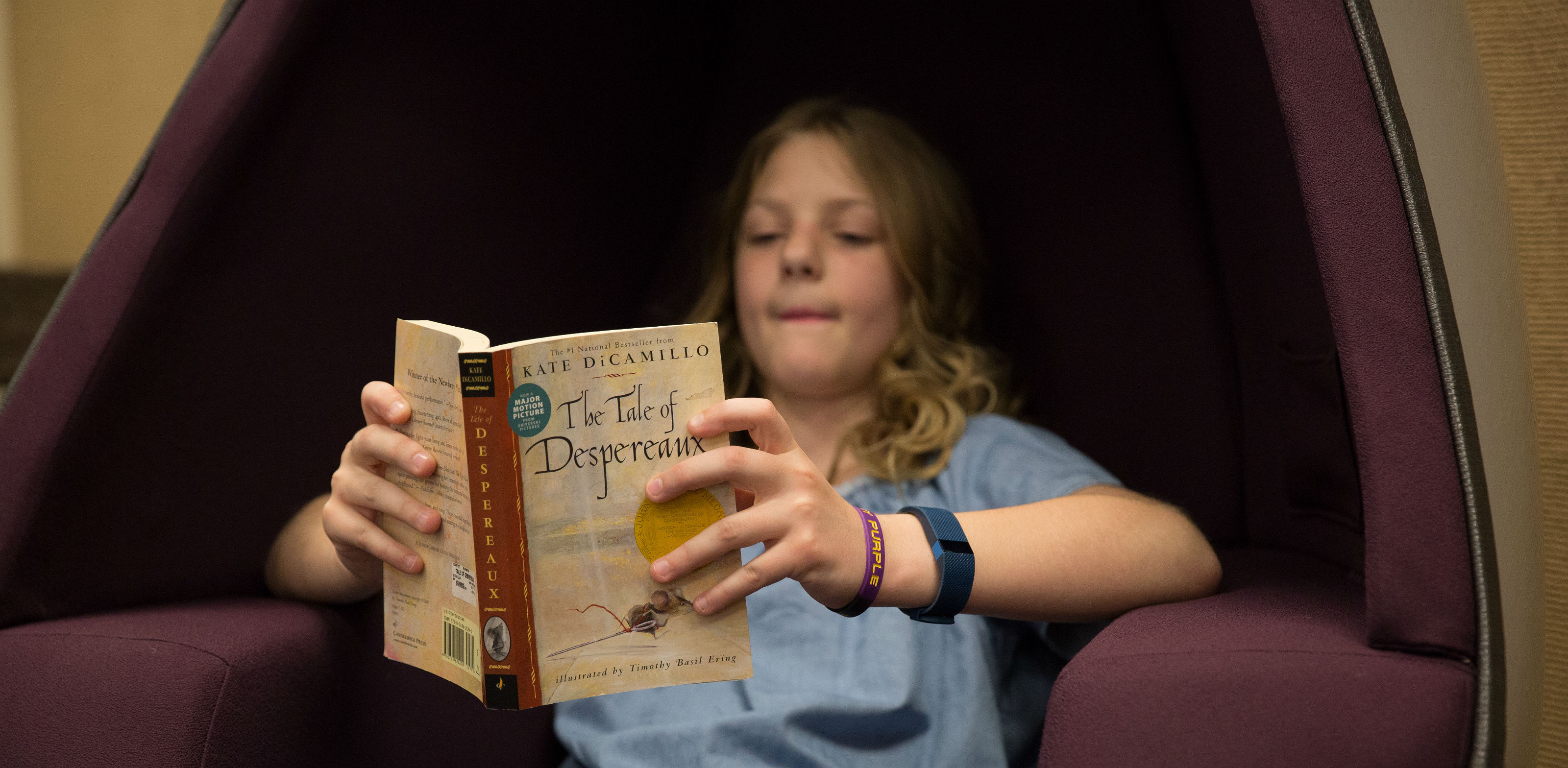 Young girl reading "The Tale of Despereaux"