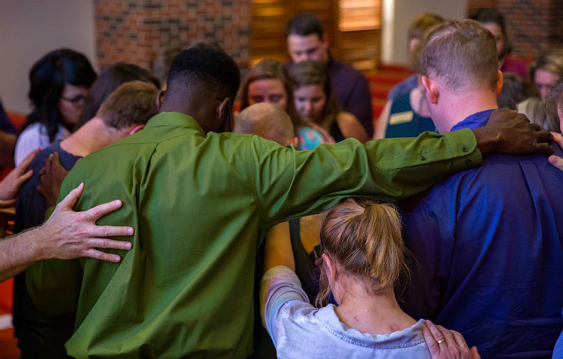 group of HSU students bowing thier heads and praying together