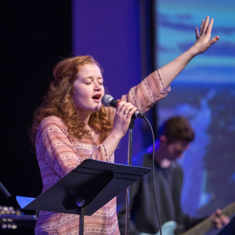HSU student singing into a microphone at worship