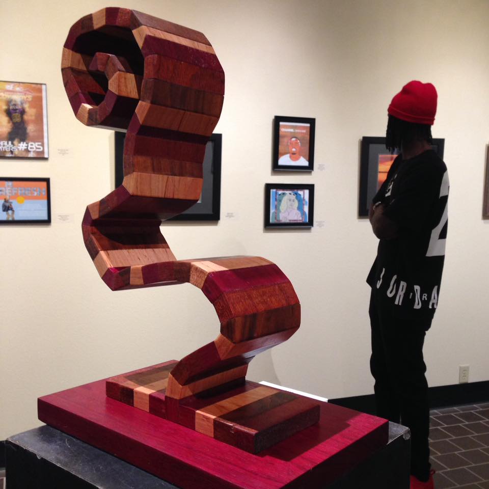 HSU student standing next to sculpture observing print art on the wall