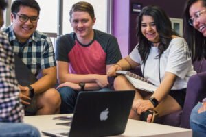 HSU students smiling and  watching video on Mac laptop