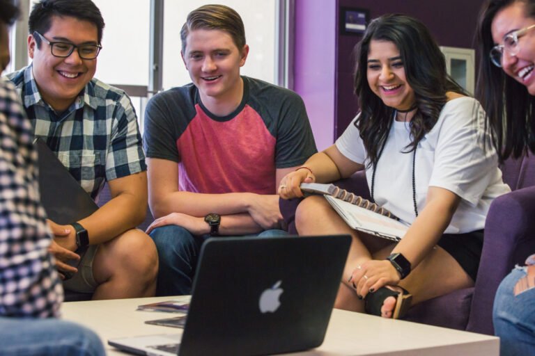 HSU students smiling and watching video on Mac laptop