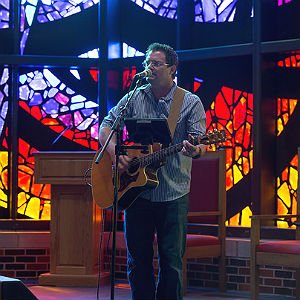 HSU Master of Music student playing the guitar and singing on stage