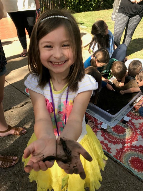 young girl holding a dirt covered worm