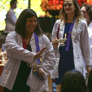 Nursing students wearing white lab coats receiving national certification at ceremony