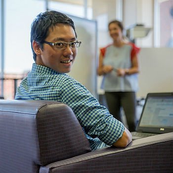 HSU Nonprofit Management student sits with his laptop looking backwards and smiling