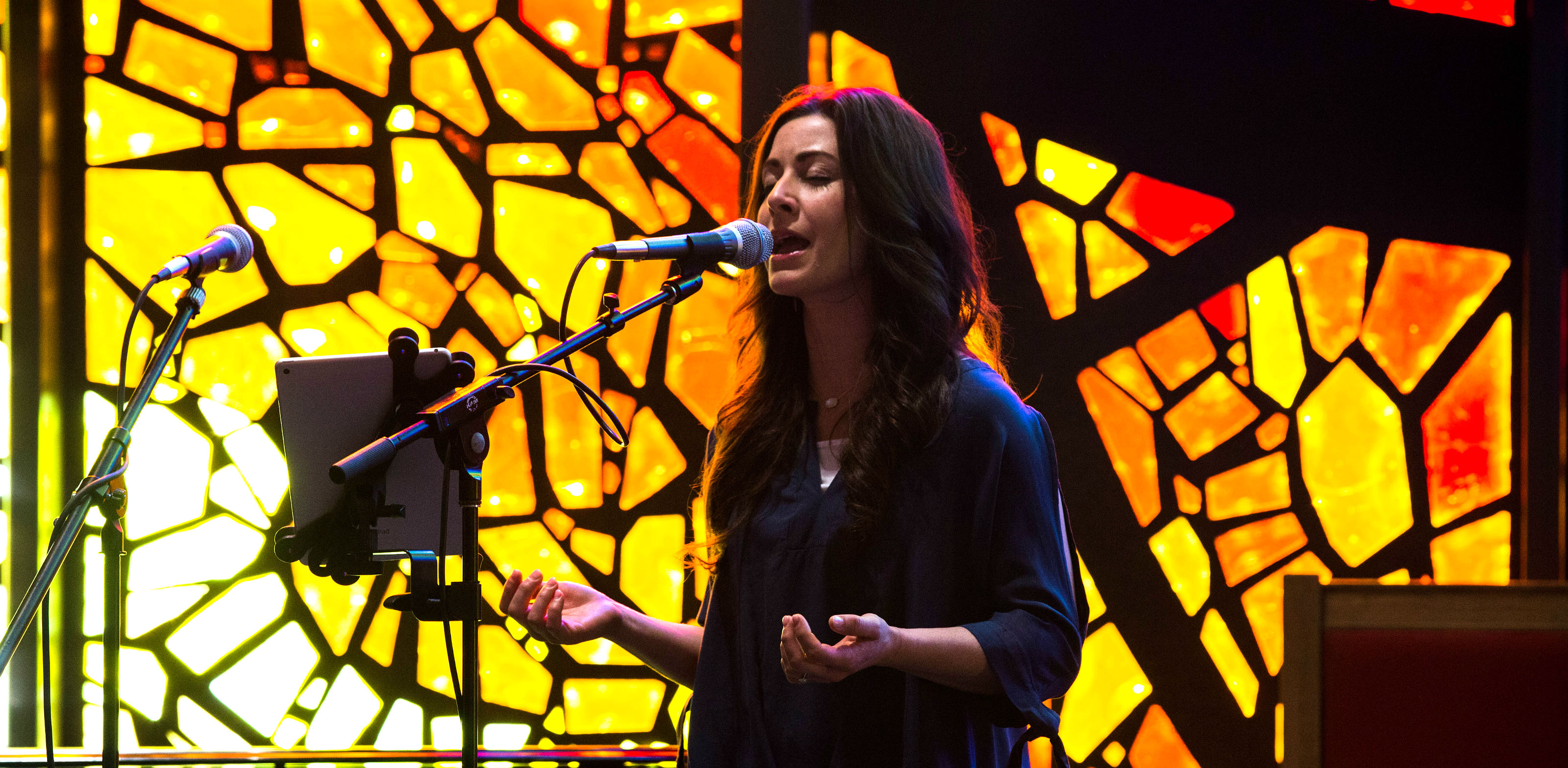 HSU Master of Music student singing into a microphone in a worship center