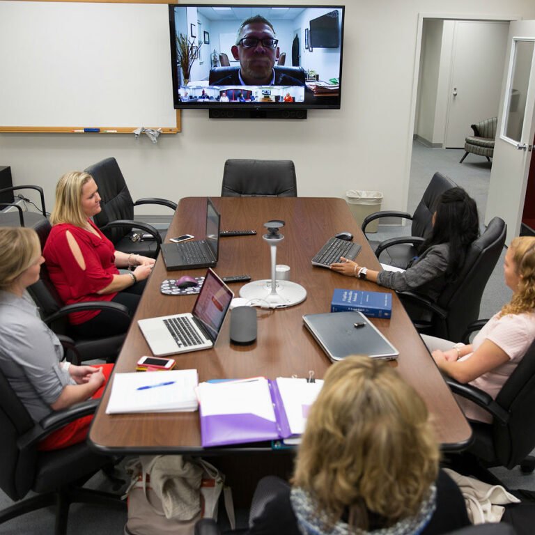 Professor delivering lecture via skype to students in a conference room