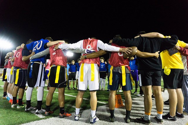 flag football team gathered and bowing their heads in prayer