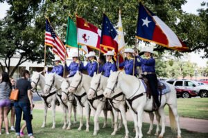 The Six White Horses riders line up on horseback with flags.