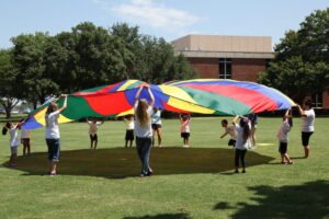 Students and teachers play with a parachute at Dream Catchers camp.