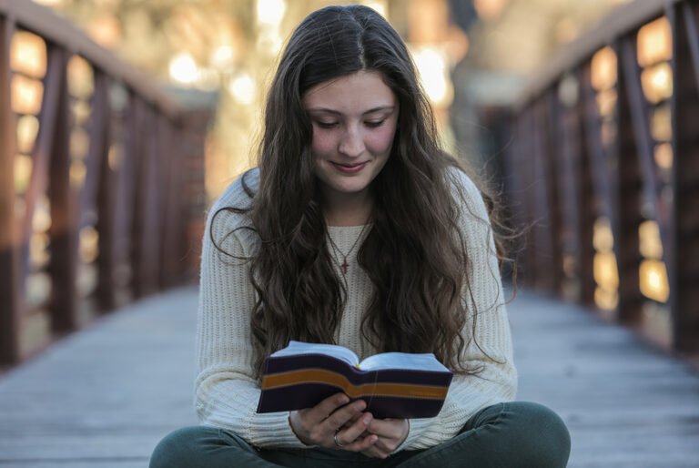 HSU student reading Bible on a bridge