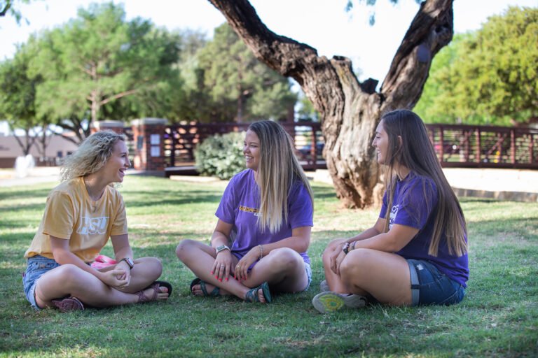 HSU students sitting in the grass on campus talking and smiling