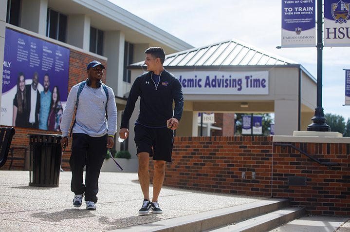 Photo of student guiding other student for direction on campus.