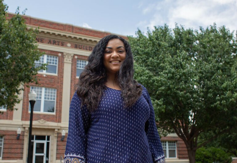 Photo of student with Music building behind them.