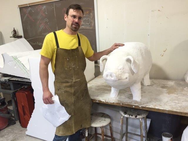 Steve Neves with large pig sculpture in an art room.
