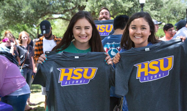 HSU graduates holding up tee shirts that read "HSU Alumni"