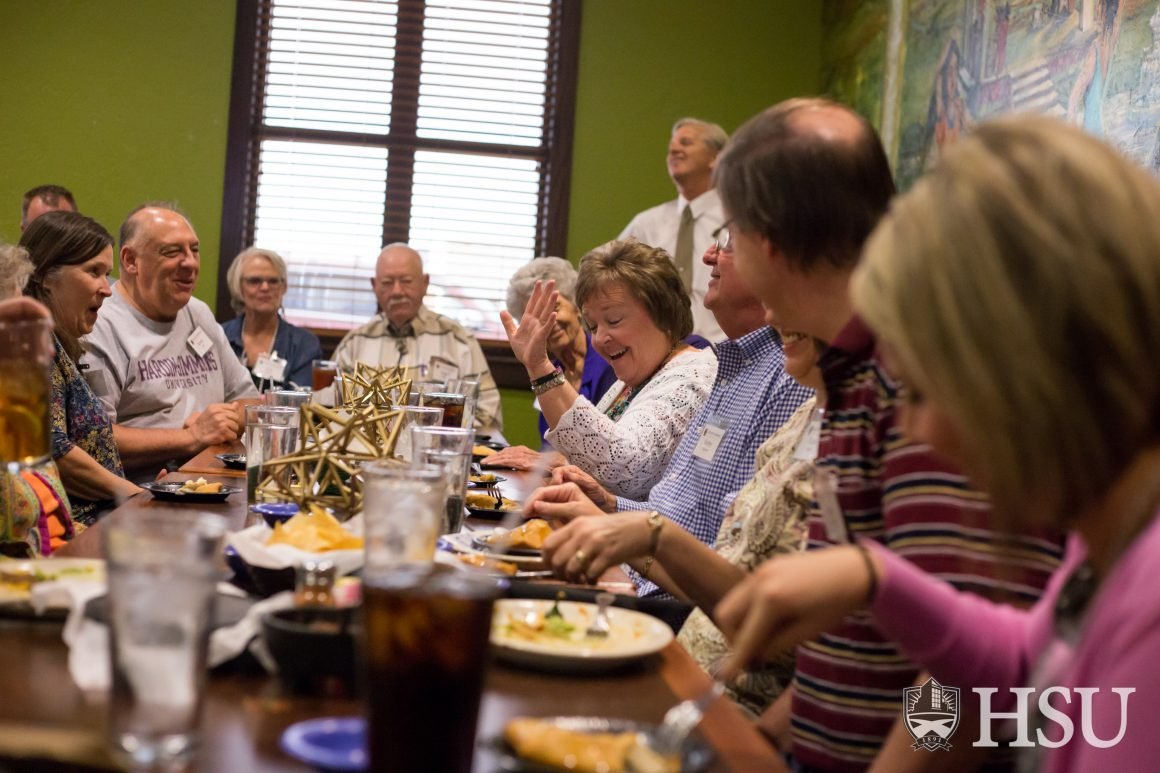 Photo of President having lunch with Alumni.