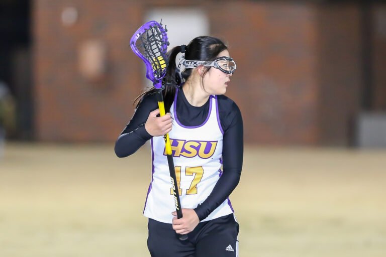A woman's lacrosse club team member playing a match.