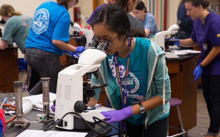 Photo of HSU student looking through microscope in laboratory.