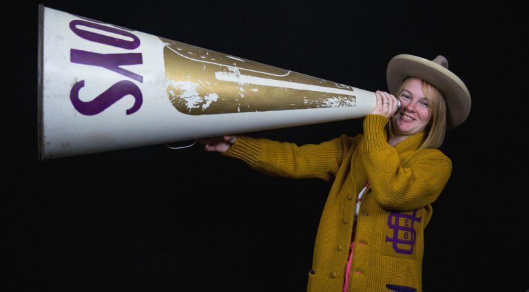 A student dressed in historic cheer outfit with giant megaphone.