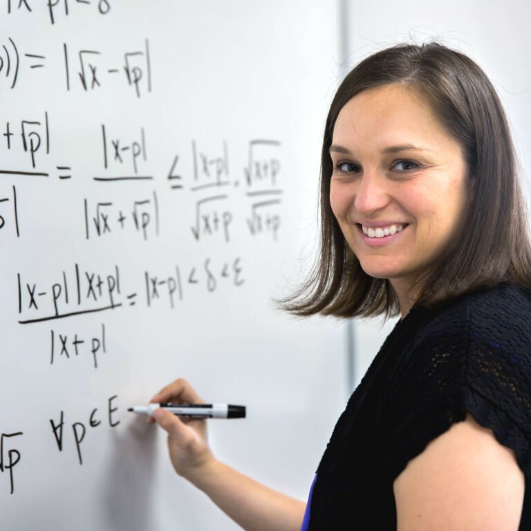 Photo of Professor writing math equation on board.