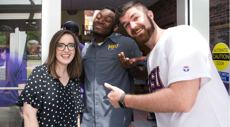 HSU students smiling in front of Student Services building