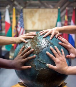 students place thier hands together on a globe