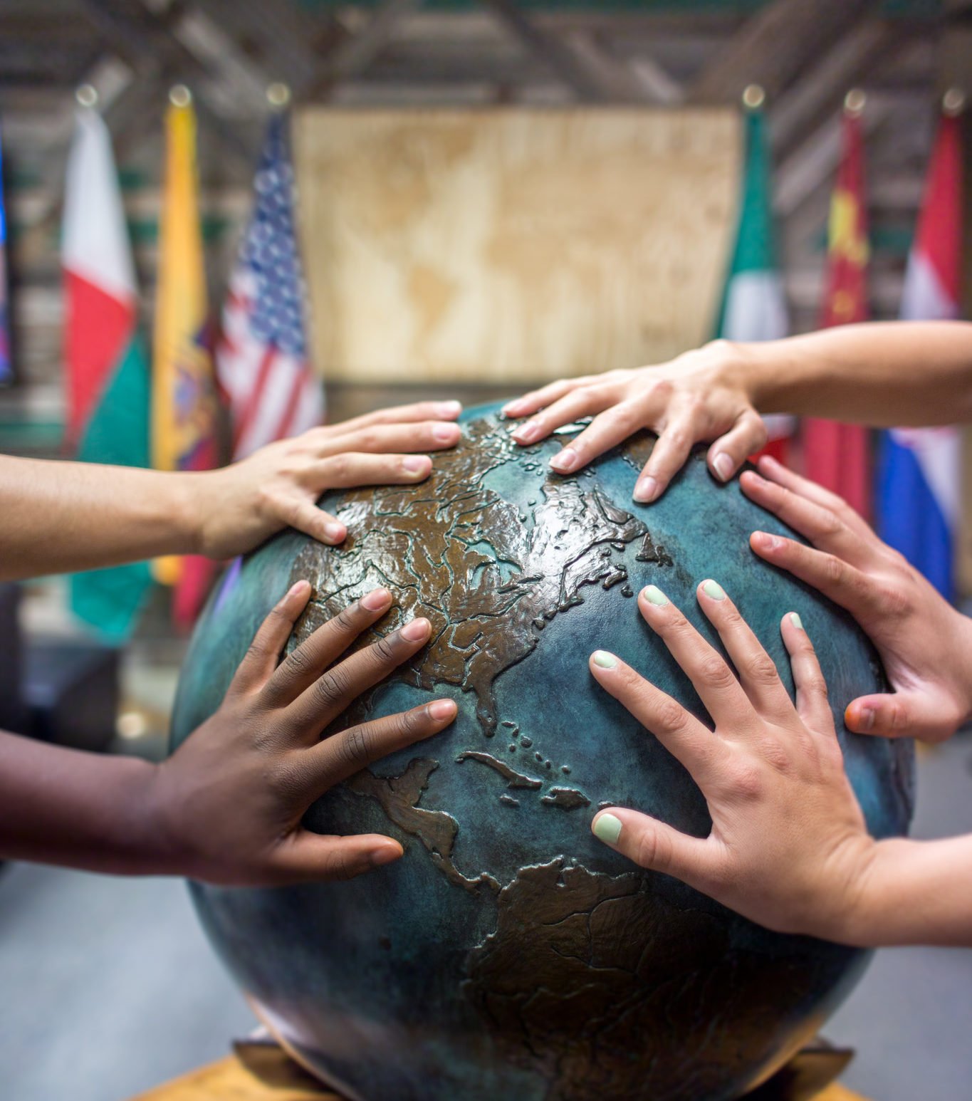students place thier hands together on a globe