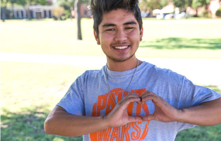 A student making a heart shape with his hands to thank donors.